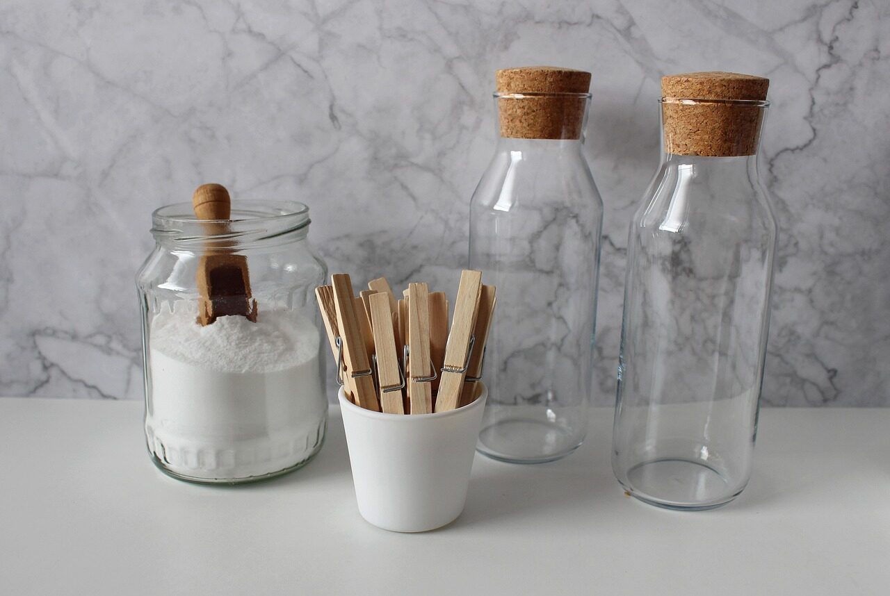 Bocal en verre contenant de la soude, pot avec des pinces à linges et 2 bouteilles en verre