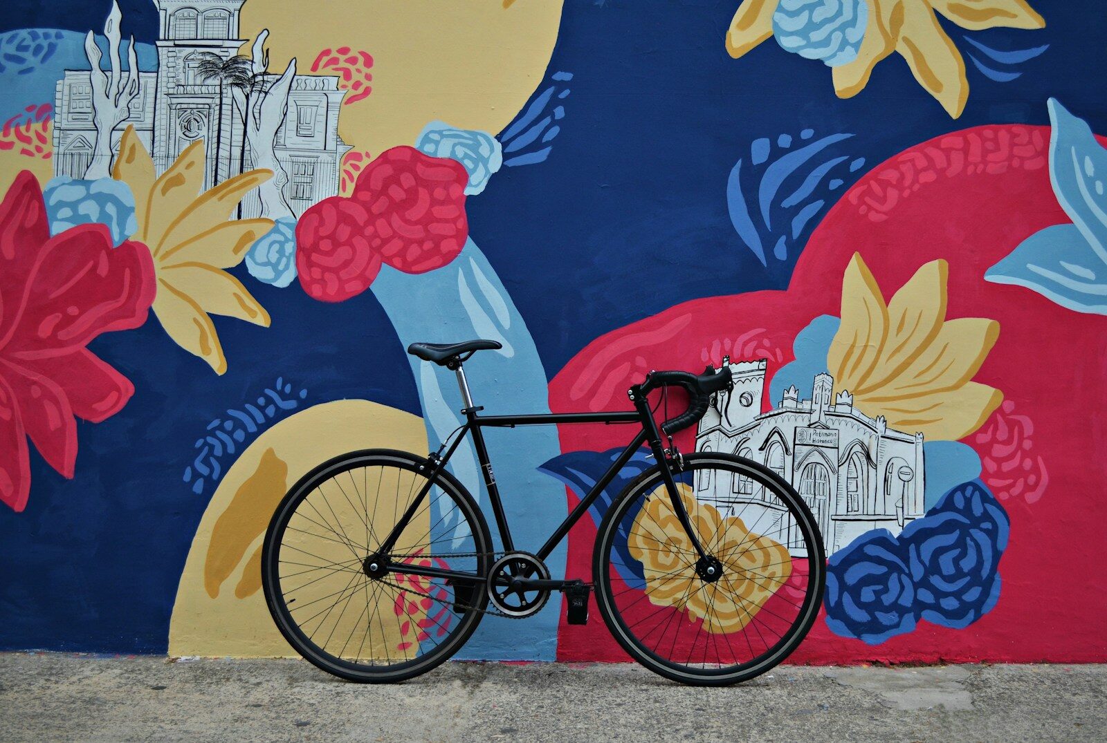Vélo noir devant une fresque murale colorée