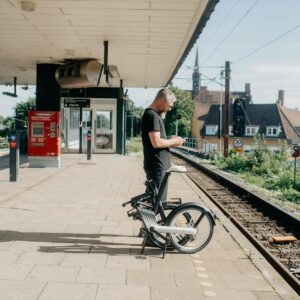 Une personne attendant son train avec un vélo pliable