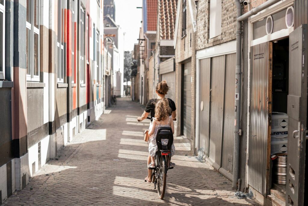 Cycliste avec une siège enfant dans une rue etroite