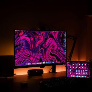 Ordinateur avec fond d'écran rose, violet, sur un bureau
